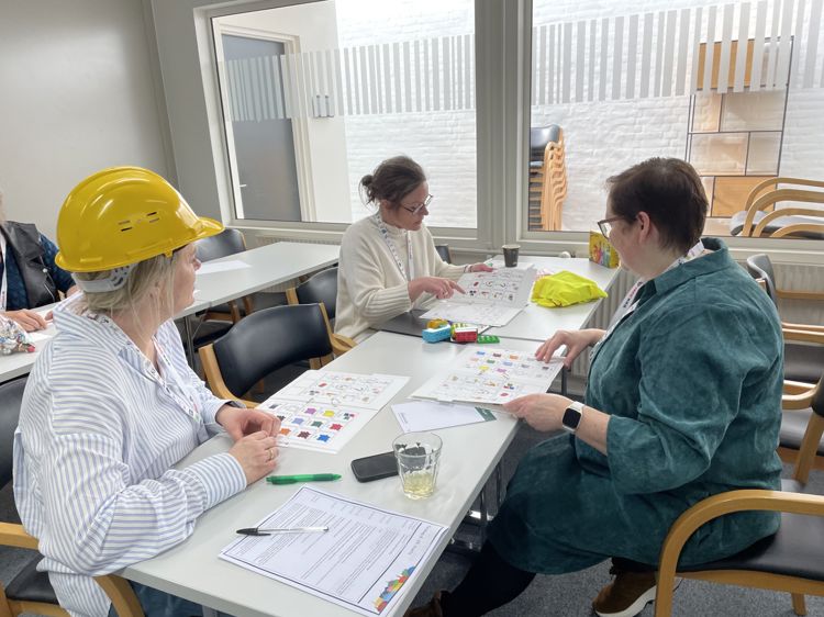 En gruppe mennesker som sitter ved et bord og jobber med ASK-symboler
